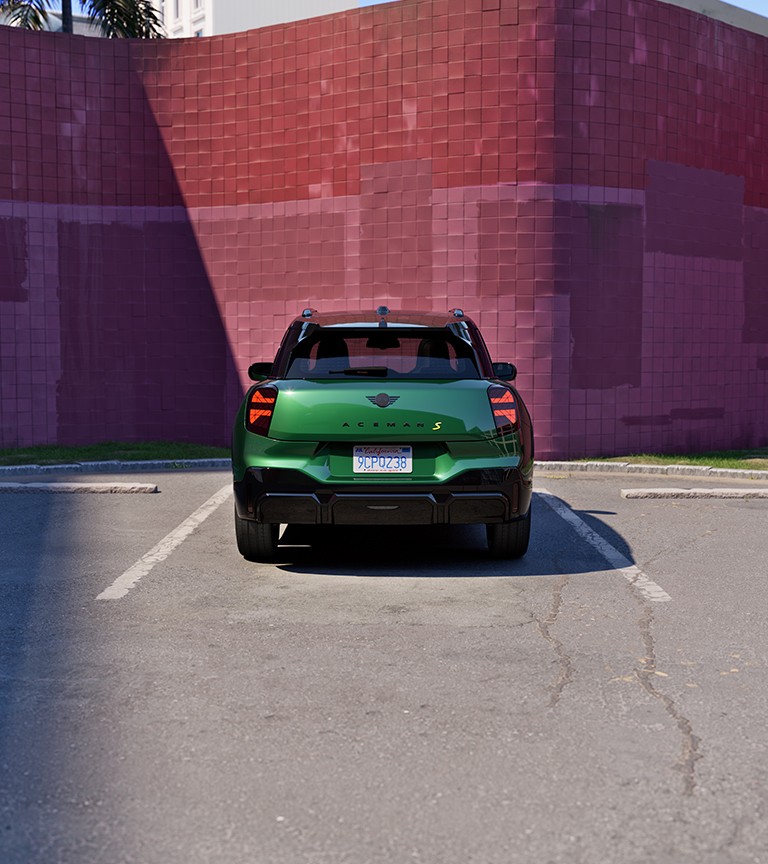 MINI Aceman visto de trás, estacionado numa rua em frente a uma fachada vermelha 
